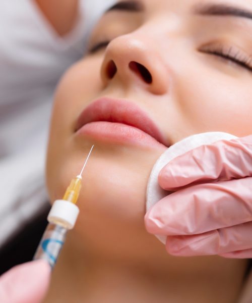 lip shape correction procedure in a cosmetology salon. The specialist makes an injection on the lips of the patient. Lip augmentation